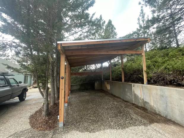 Timber-frame carport built into hillside