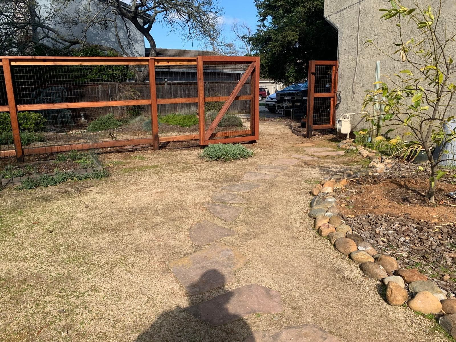 Redwood-framed welded wire nature fencing with a Z-braced drive gate and matching pedestrian gate, with a flagstone stepping path