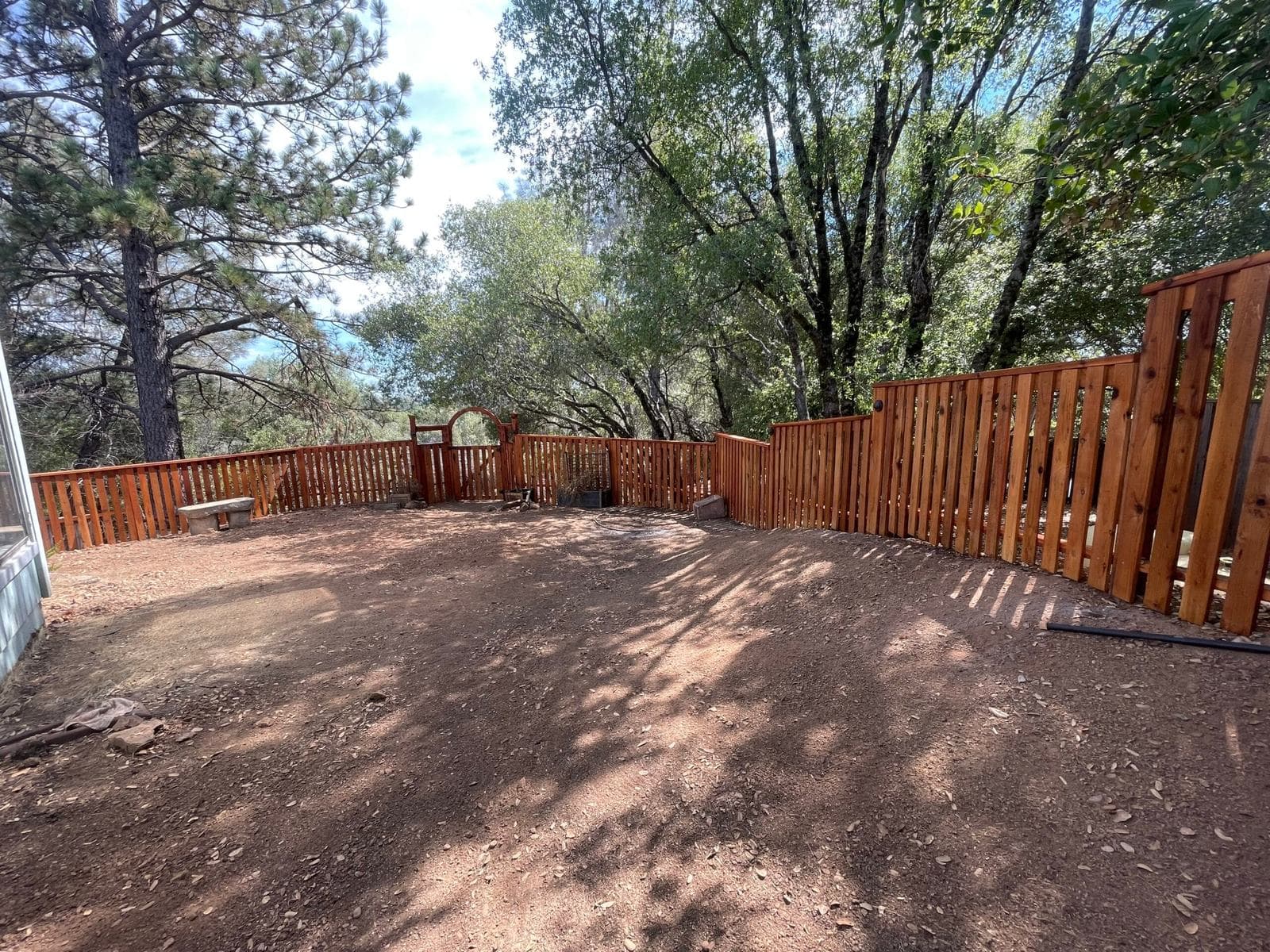 Complete redwood picket and privacy fence line stepping with the grade around a cleared foothill yard
